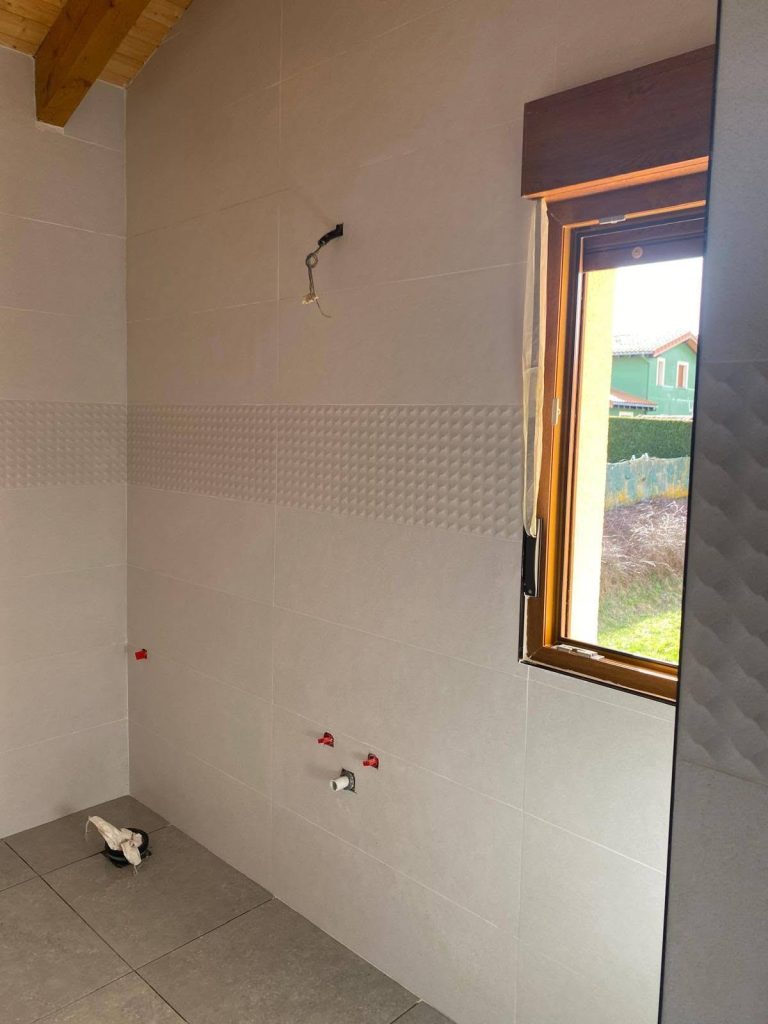 Alicatado de baño con cenefa decorativa junto a la ventana