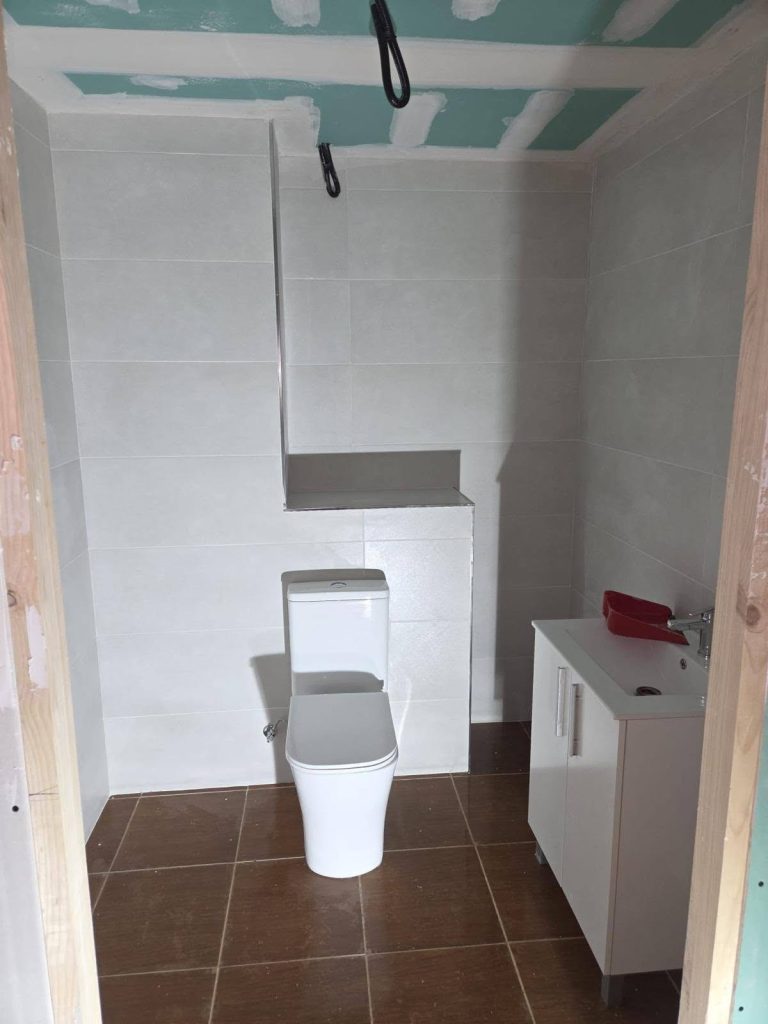 Baño reformado por completo con inodoro, mueble de lavabo y alicatado