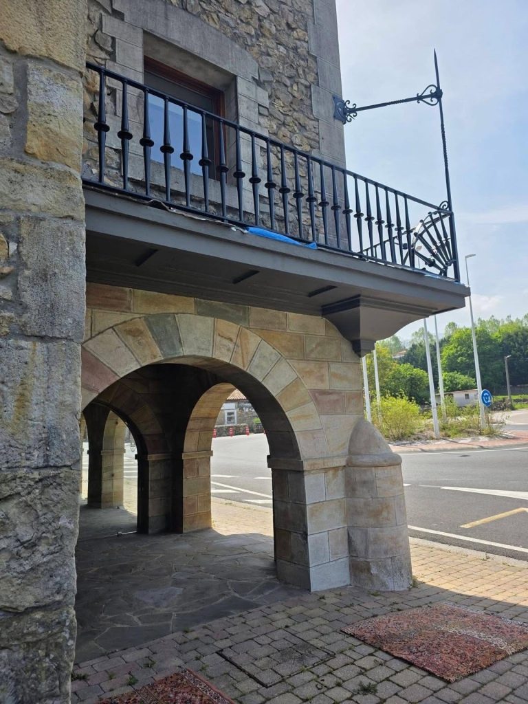 Arco de sillería de piedra rehabilitado con balcón de forja
